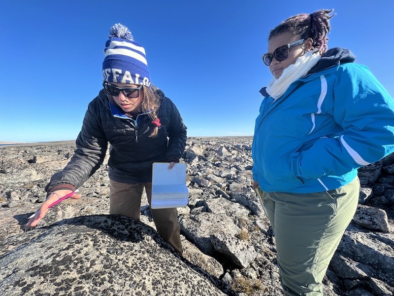 University @ Buffalo graduate students Karlee Prince and Liza Wilson examine a glacial erratic left by the ice sheet as it moved over the landscape Field work by two graduate students